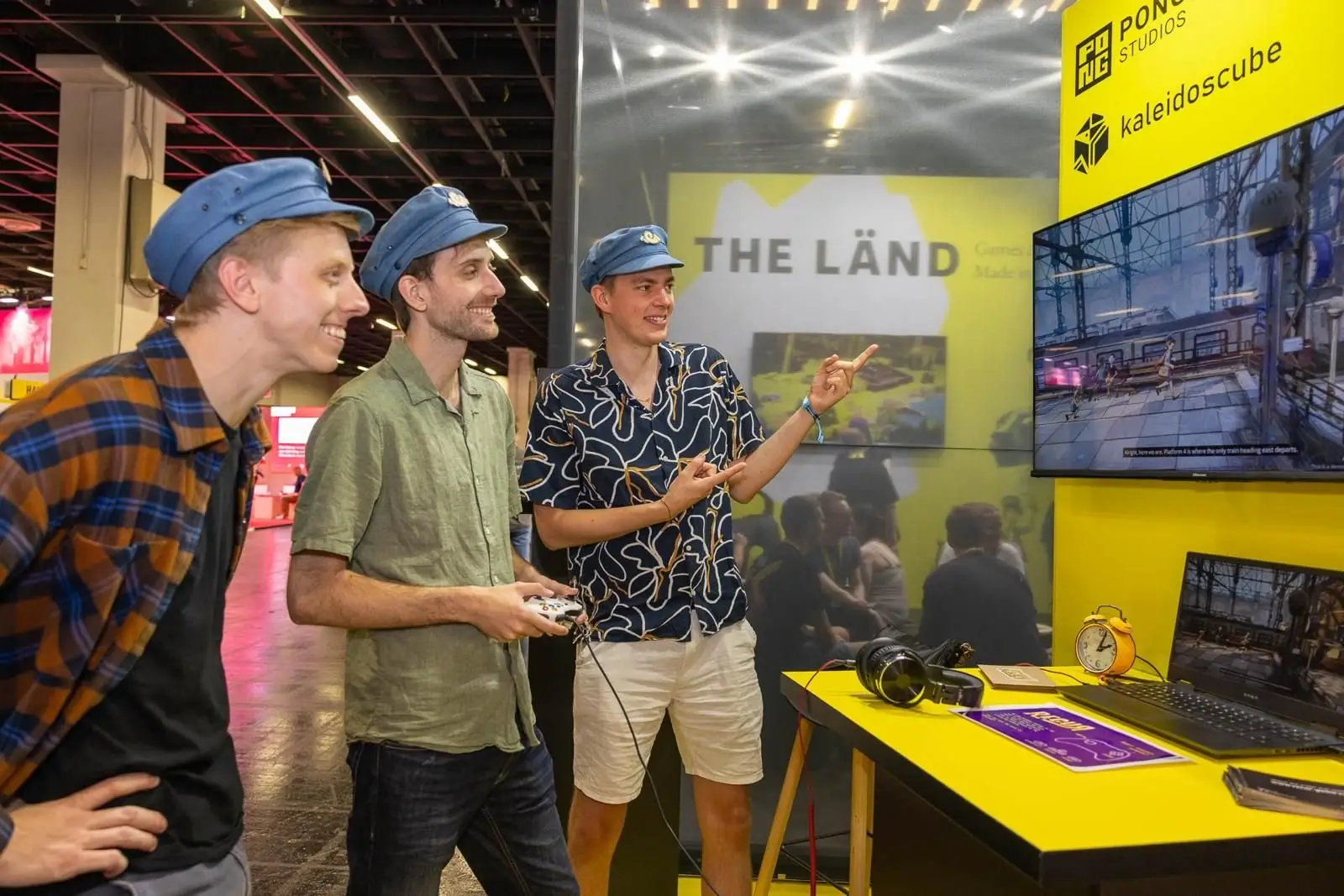 Three team members in matching caps playing a game at the THE LÄND booth