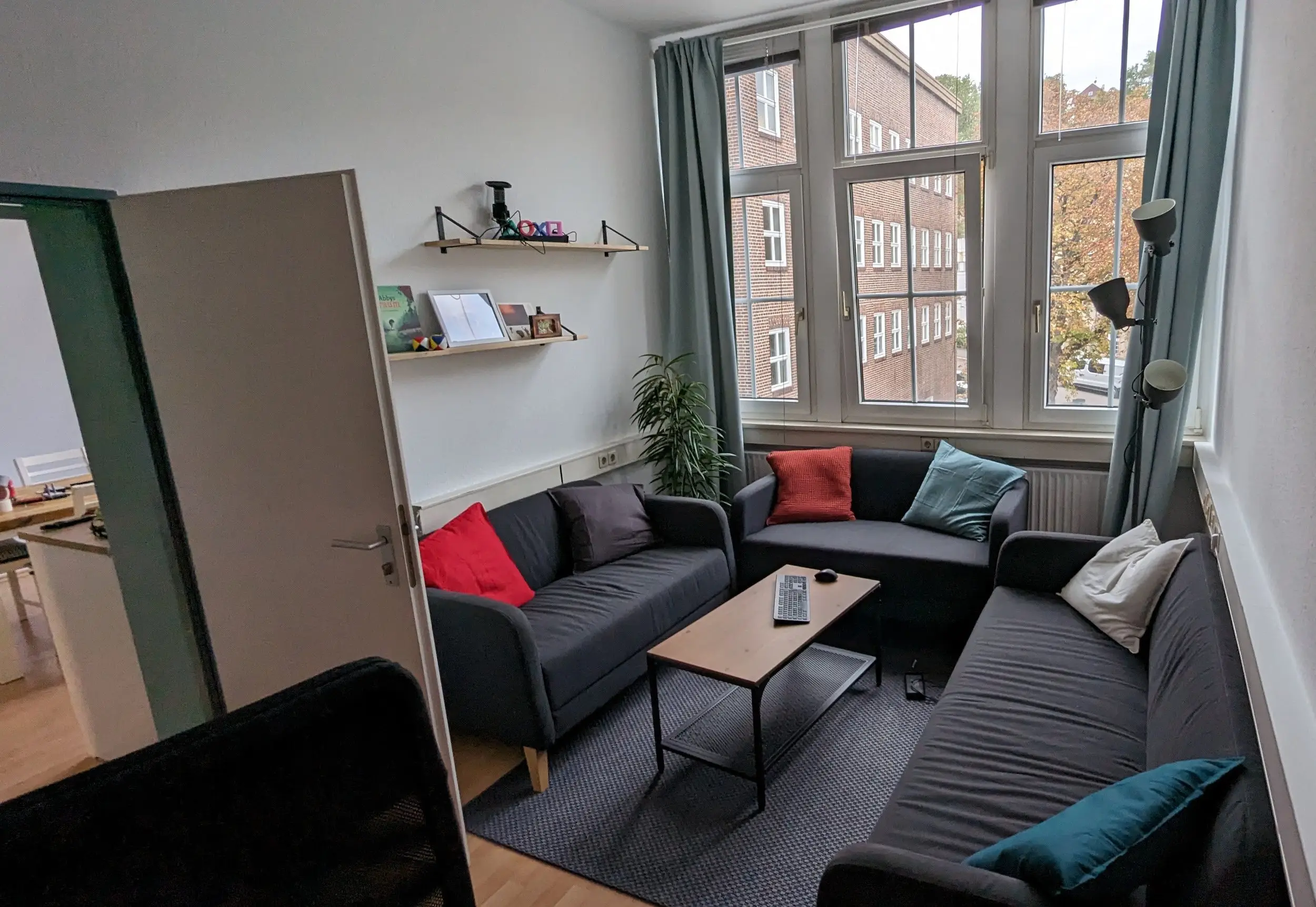 The studio lounge with grey sofas and cushions under tall windows